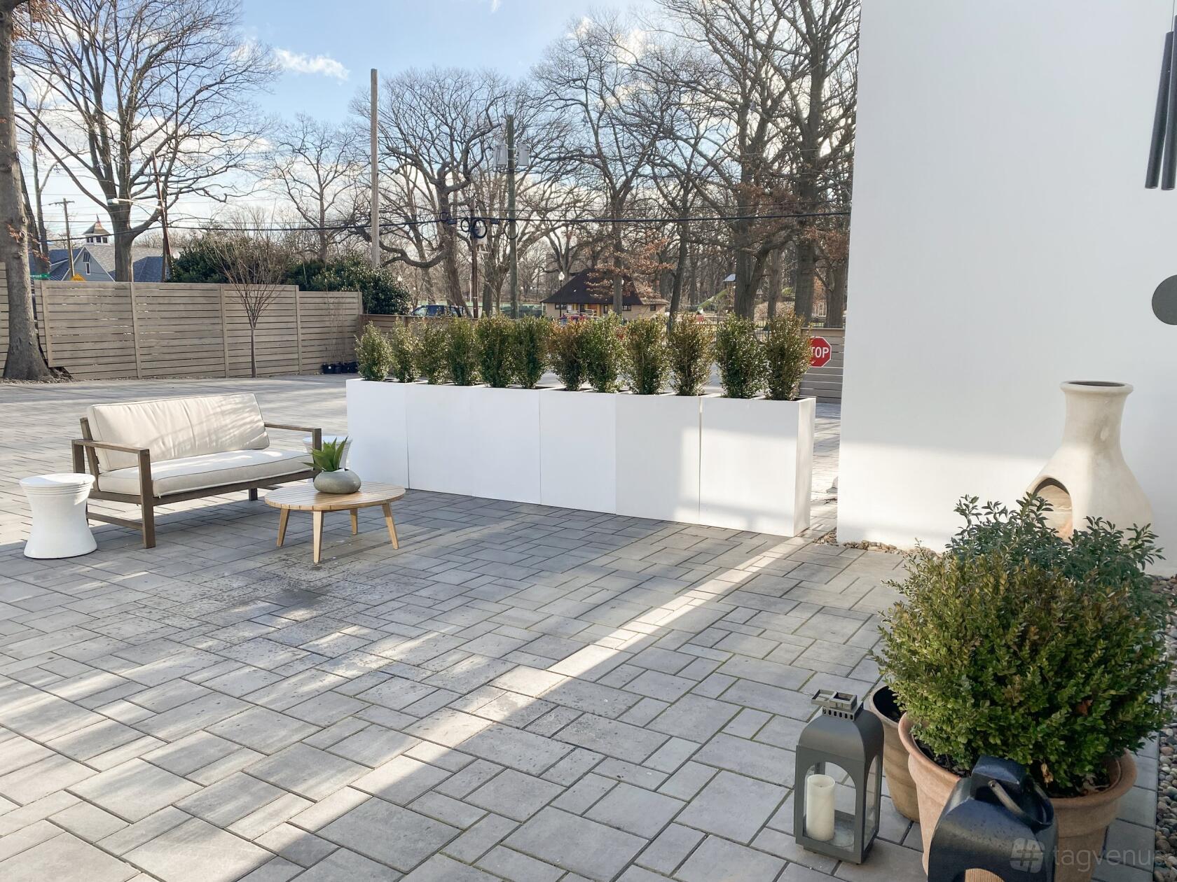 An outdoor patio with a cushioned bench, potted plants, and modern planters at Loop Studios Inc.