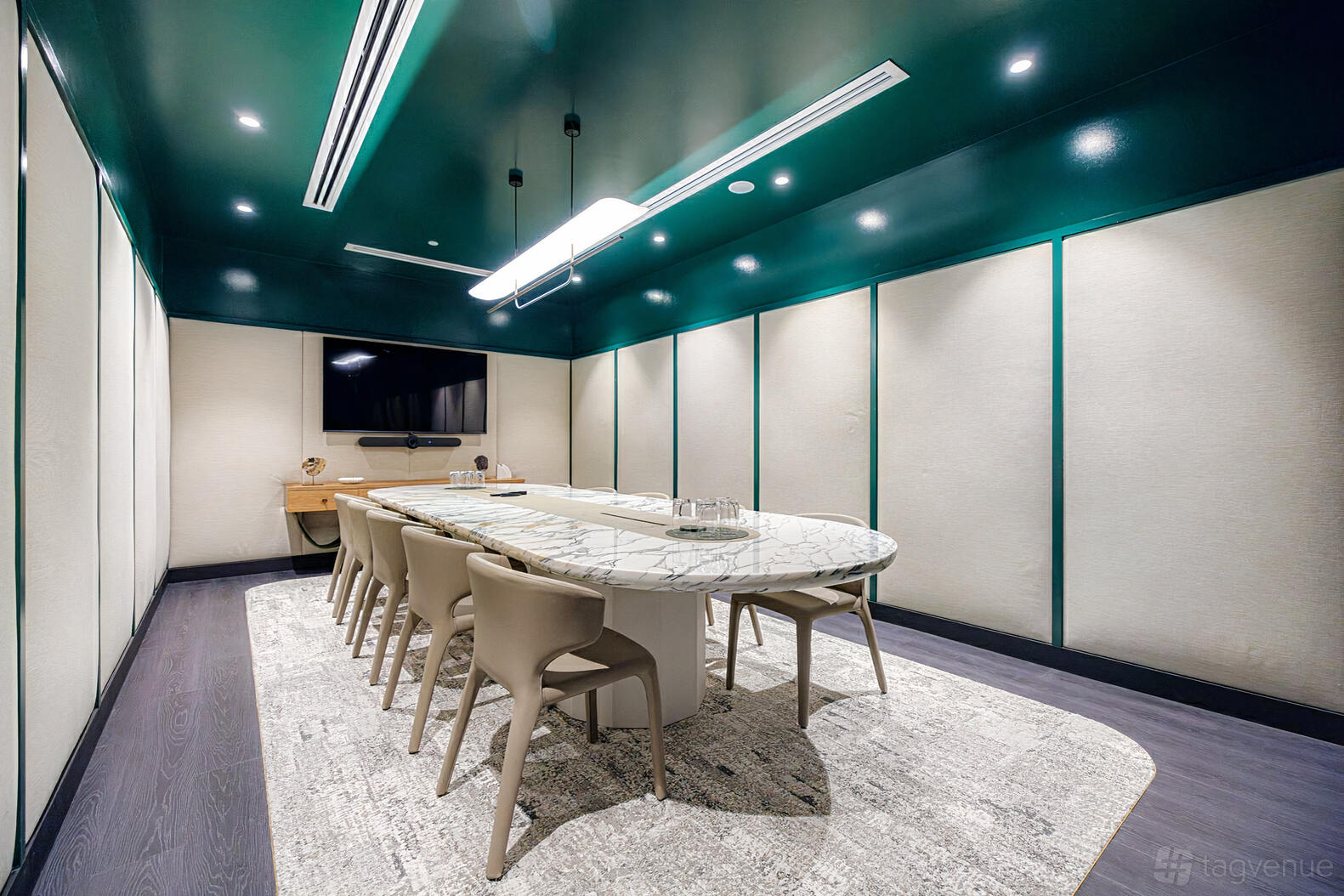 A boardroom with a marble conference table, built-in screen, and soft lighting at The Great Room.