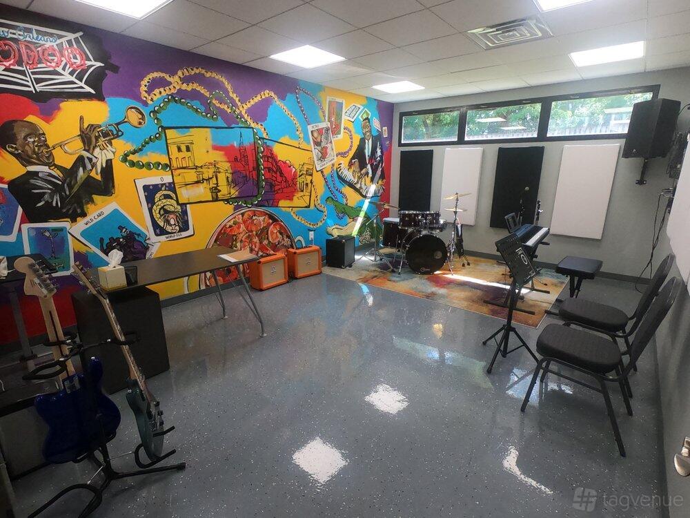 An event venue with colorful music-themed mural, drum kit, guitars, and seating at Crescendo Studios.
