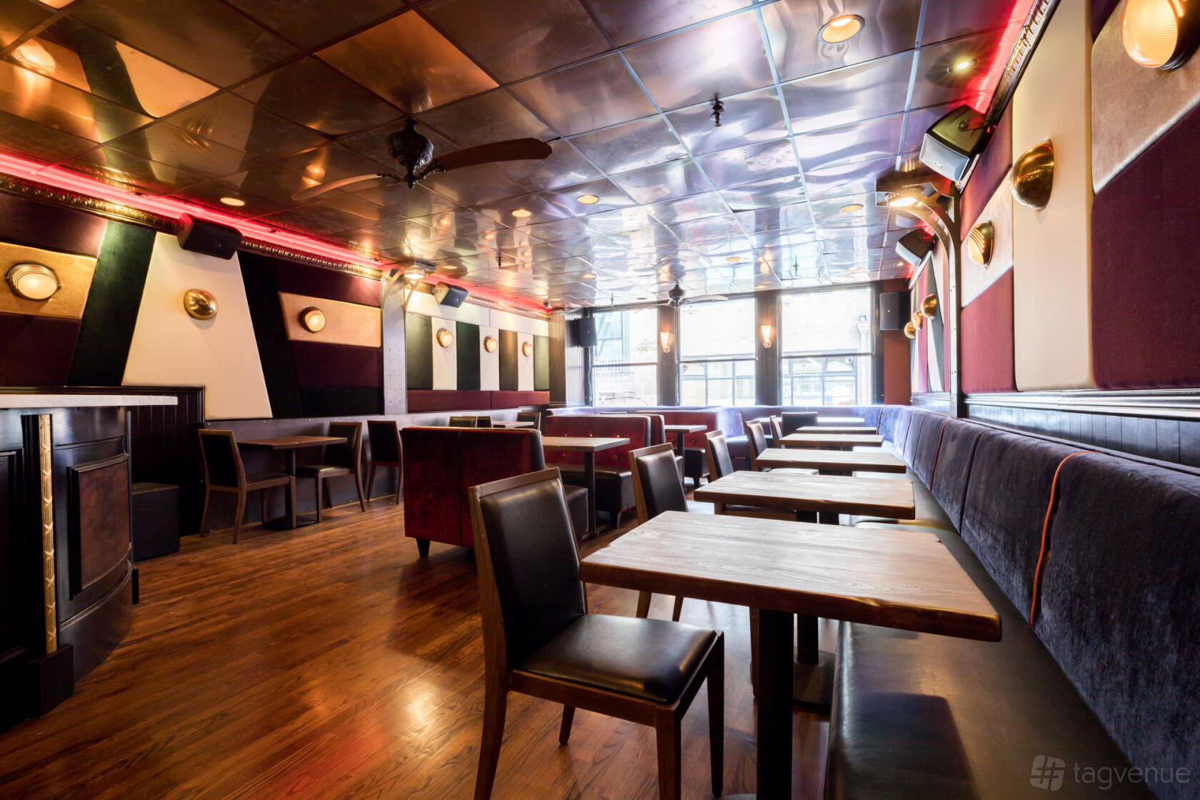 An event space with wood flooring, velvet banquette seating, and brass wall sconces at Toy Soldier.