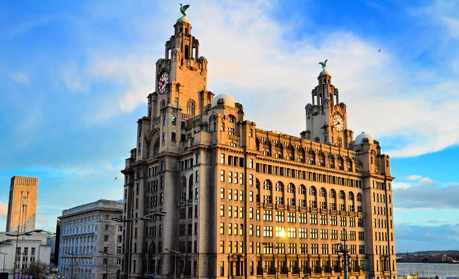 An iconic stone building with twin clock towers and rooftop sculptures at The Royal Liver Suite.