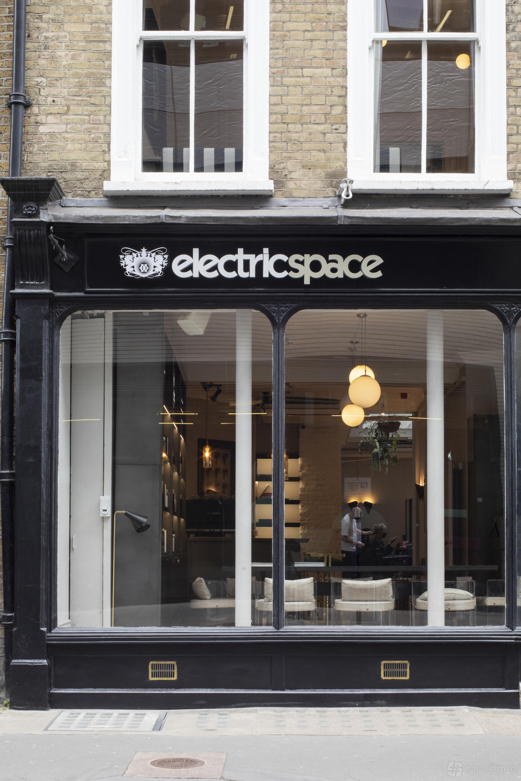 A historic building with large front windows, globe pendant lights, and a black facade at Electric Space.