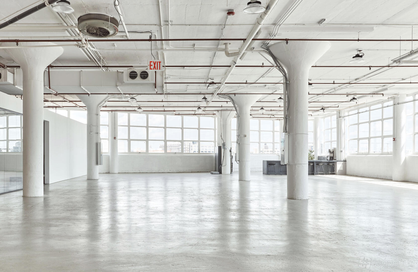 A photo studio with large industrial windows, white columns, and polished concrete floors at Mayo Studios.