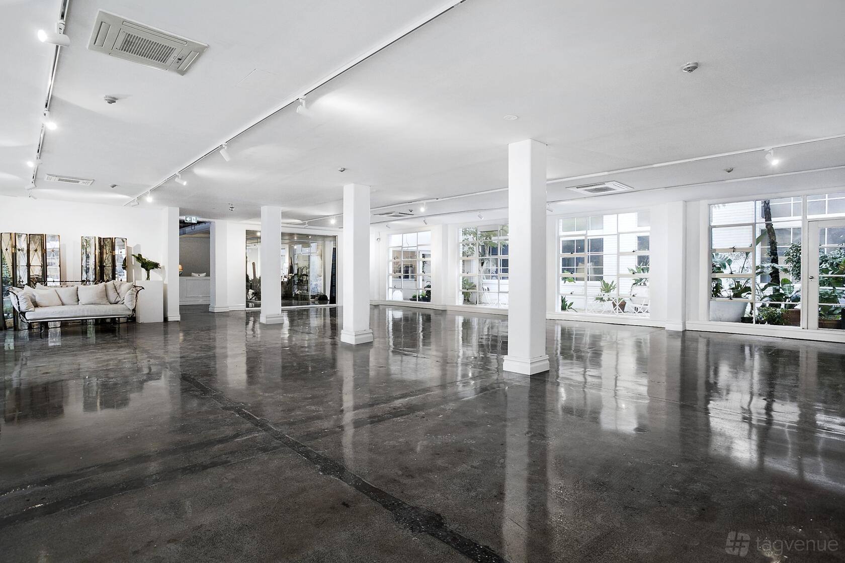 An event venue with polished concrete floors, white walls, and large windows at La Porte Space.