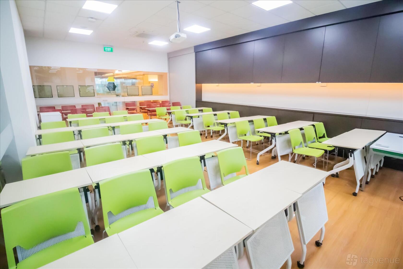 A classroom with green and white chairs, white desks, and wood flooring at ERC Institute