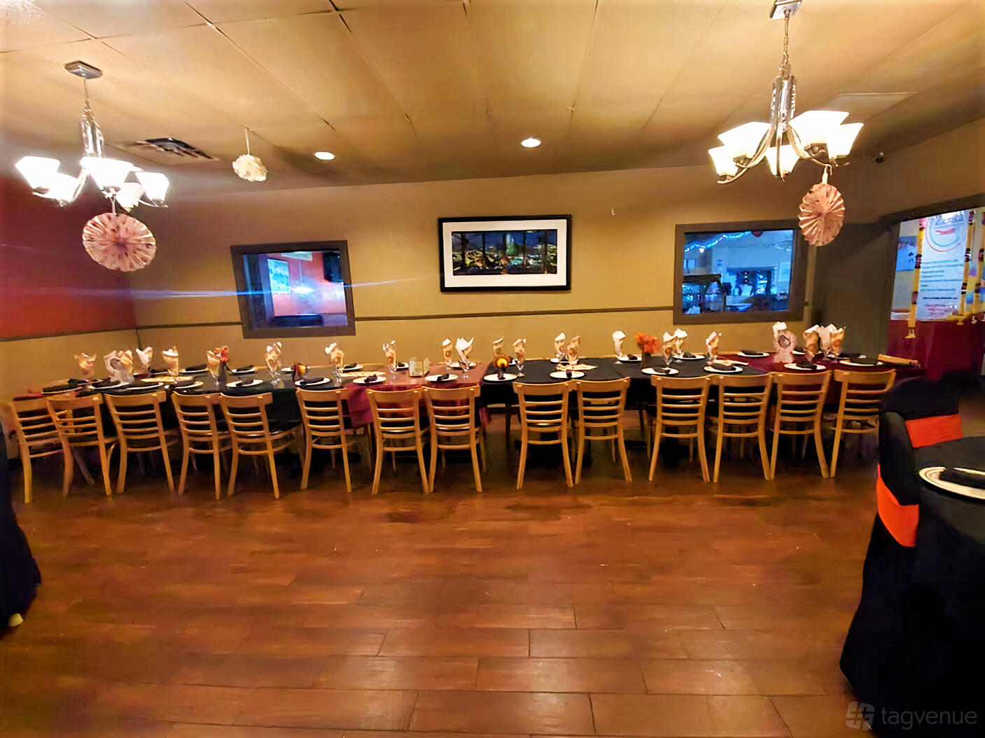 An event space in a restaurant with a long banquet table set with folded napkins and wooden chairs at Zaika Indian Cuisine.