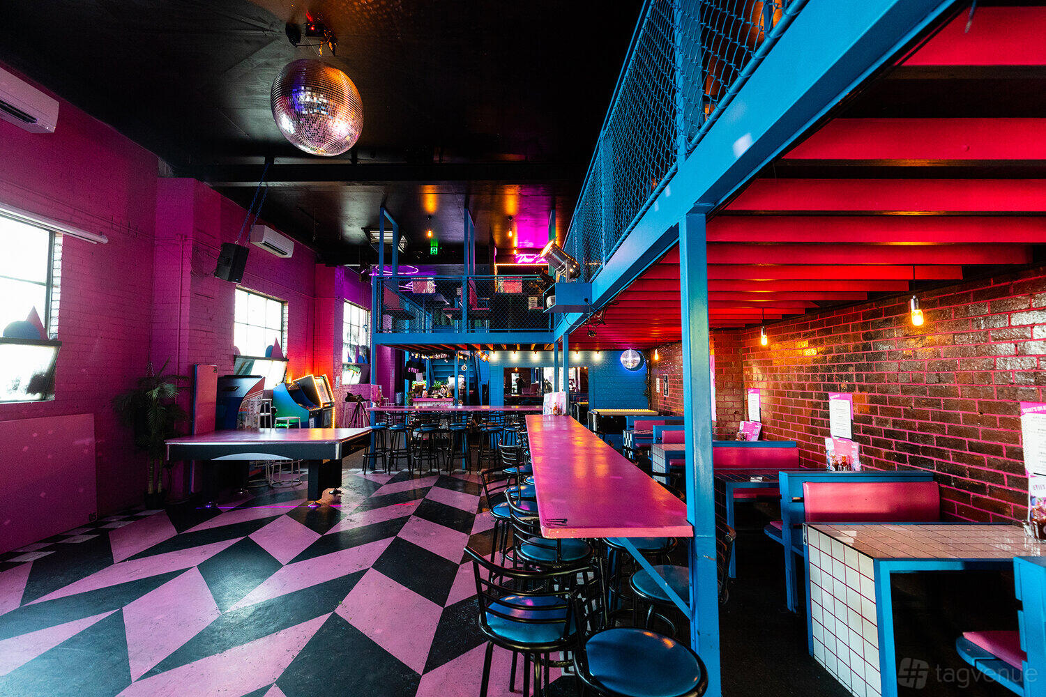 A bar with chevron patterned floors, neon lighting, a disco ball, and colorful seating at Evie's Disco Diner.