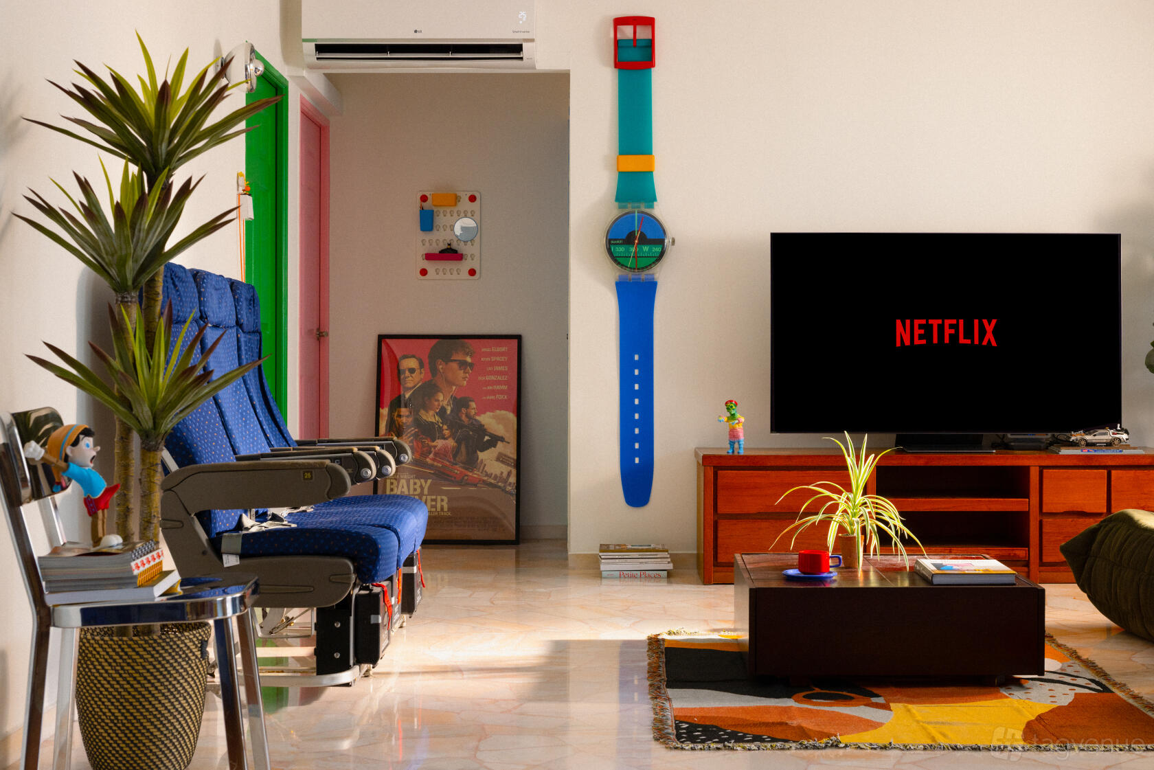 A photo studio with airplane seats, retro decor, wall art, and a large TV in the Kitschy Eclectic Apartment at Tampines HDB.