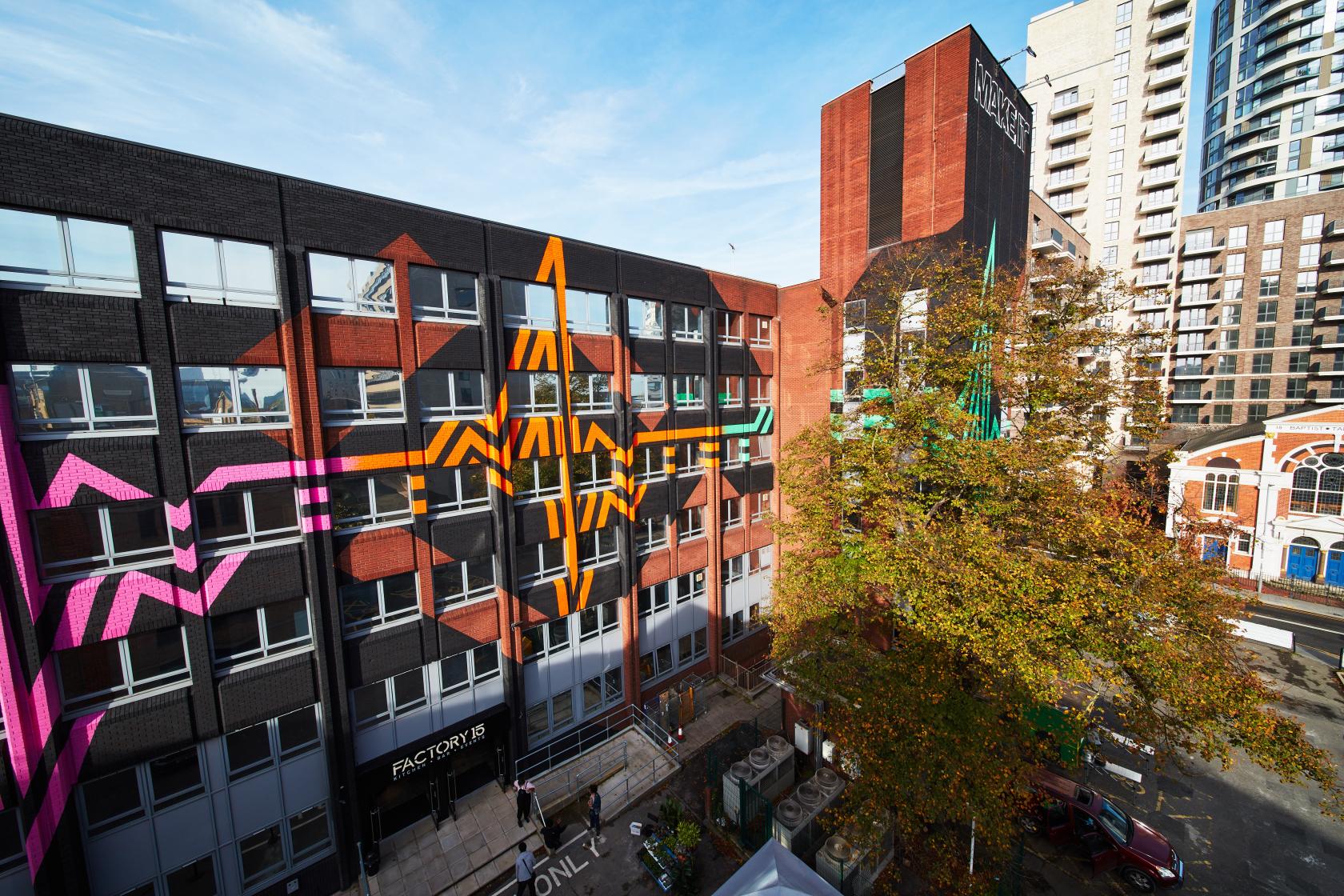 A versatile event space with colorful geometric murals on a multi-story building exterior at MAKE IT Barking.