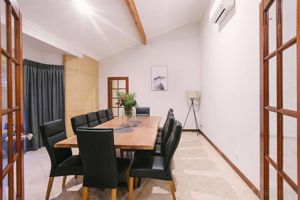 A hotel meeting room with a long wooden table, black leather chairs, and decorative plants at Eight Willows Retreat.