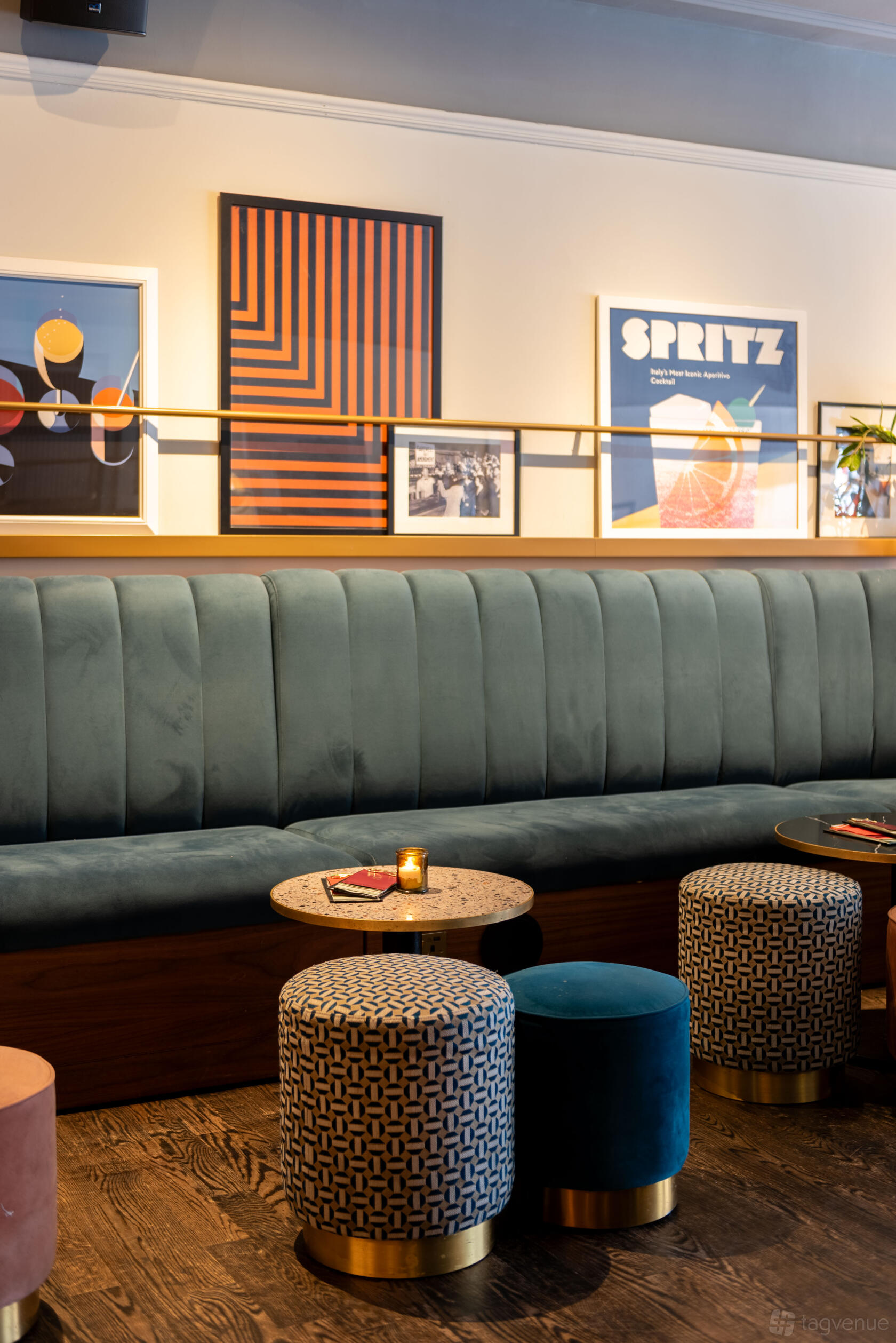 An event space in a cocktail bar with a plush green banquette, framed artwork, and small round tables at LOCKES Bar Covent Garden.