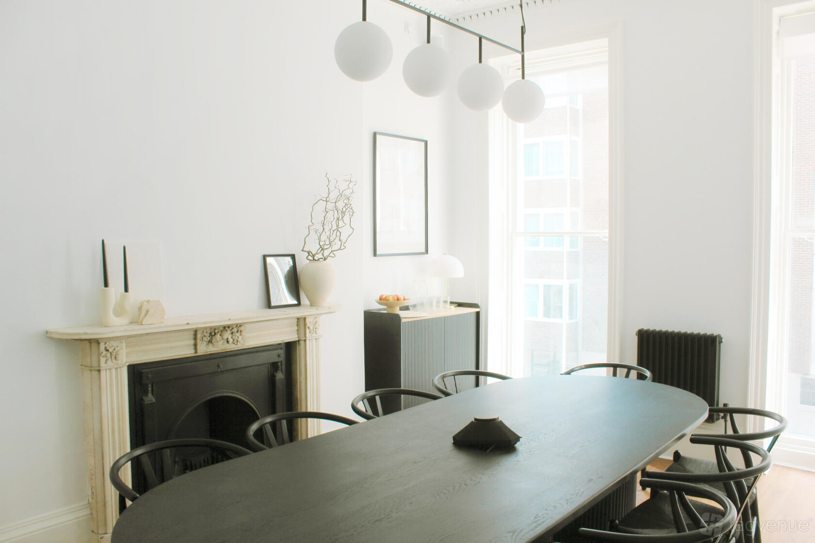 An event venue with a black oval table, minimalist decor, and globe pendant lights at 34 Bloomsbury.