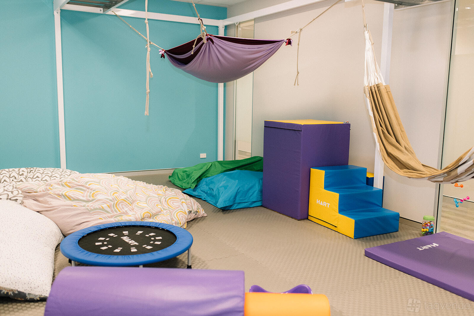 A therapy room with padded mats, soft play blocks, bean bags, and hammocks at Inside Out Therapy.