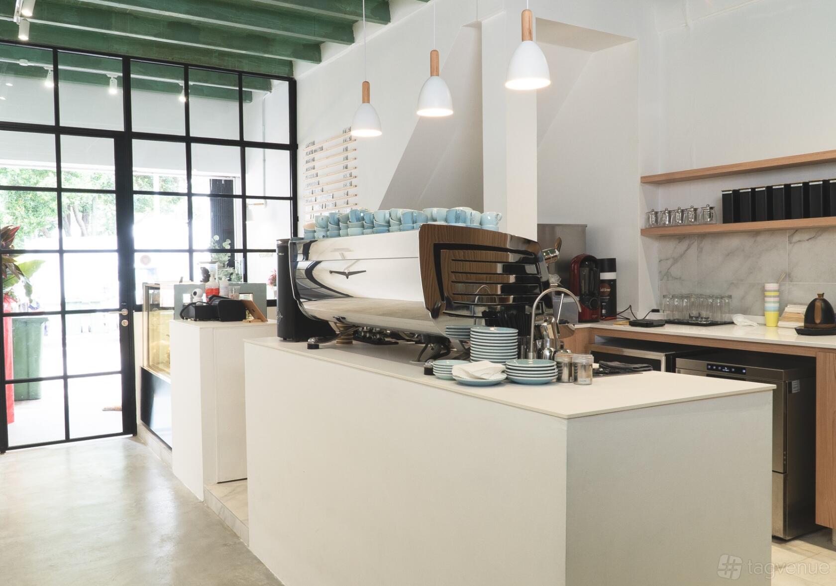 A cafe interior with a large espresso machine, marble countertop, and pendant lighting at Main Street Commissary.