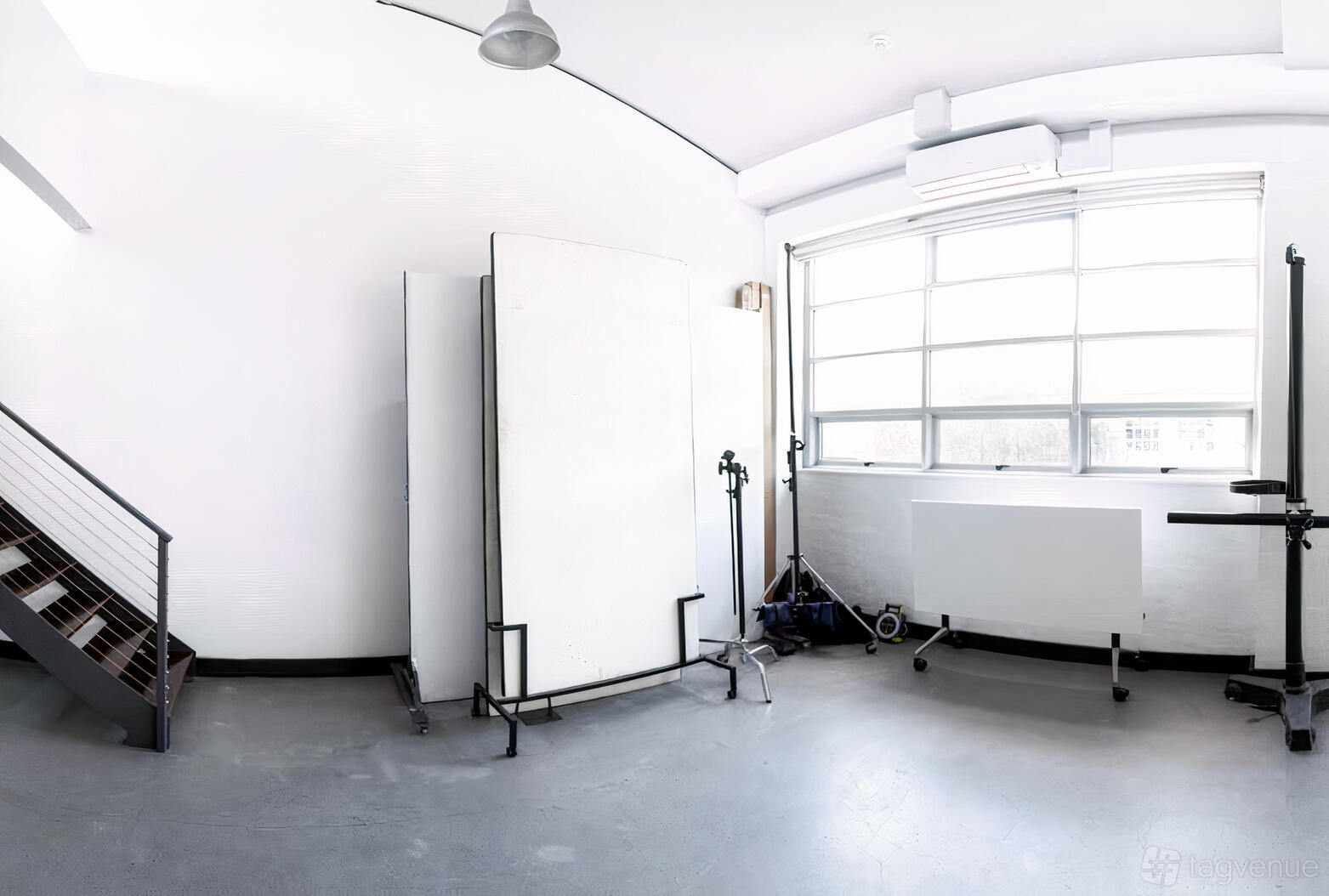 A photo studio with large industrial windows, movable backdrops, and concrete floors at Wave Particle.