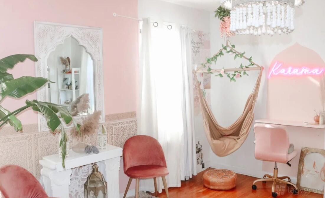 A photo studio with pink accent walls, velvet chairs, a hanging hammock, and a neon sign at Pink Moroccan Studio.
