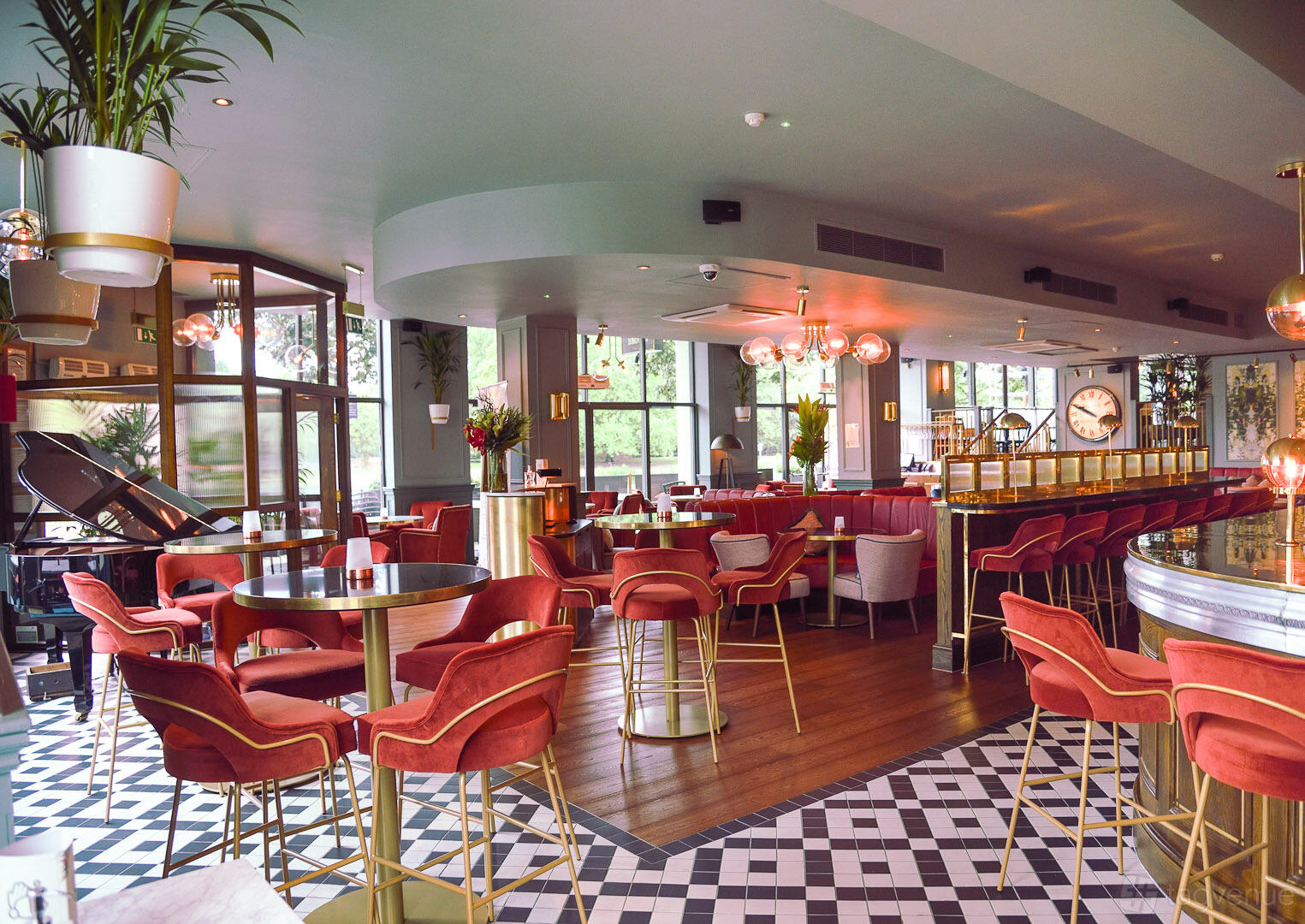 A restaurant with red velvet chairs, gold accents, large windows, and a tiled floor at Browns Kingston.