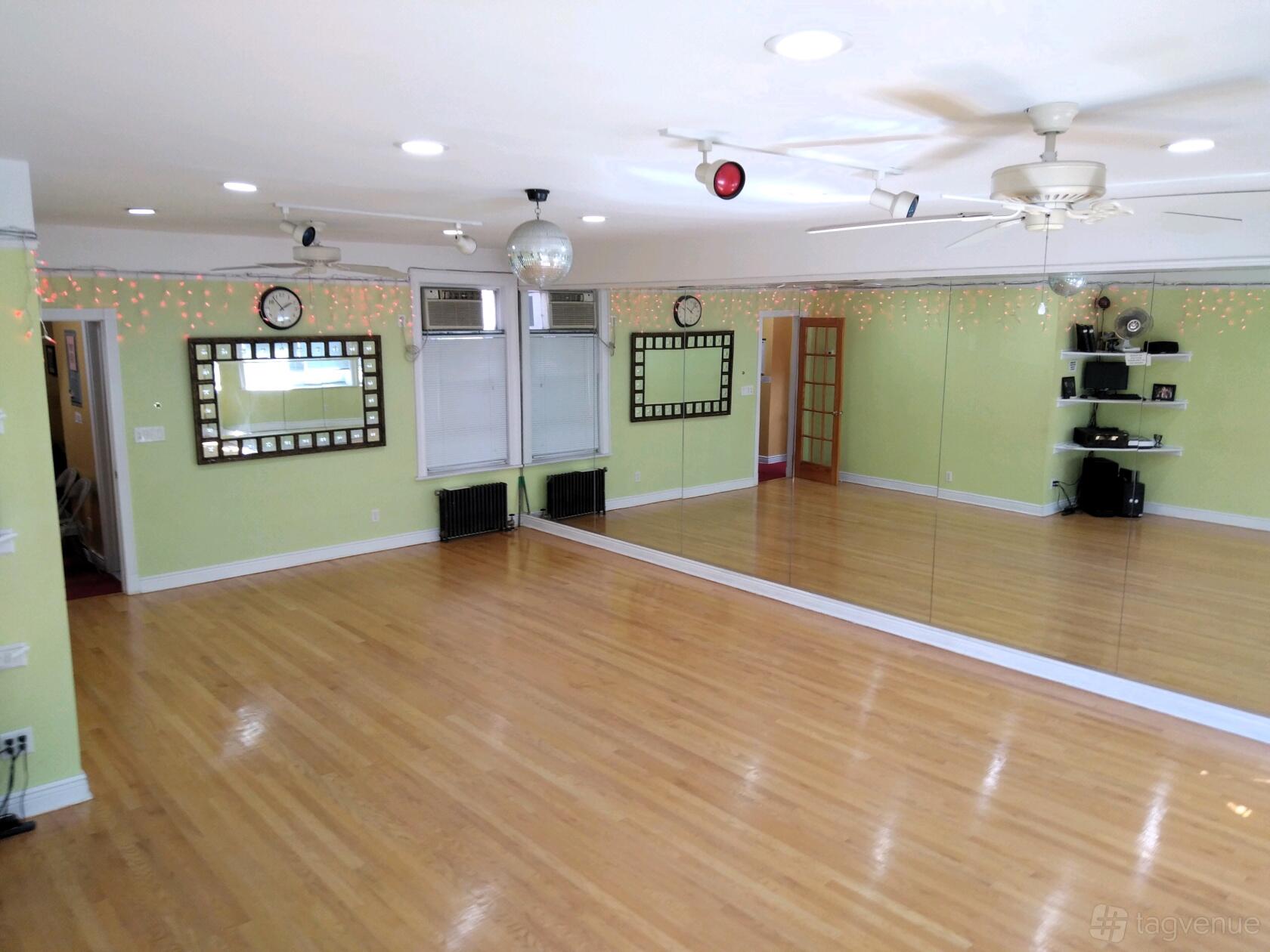 A dance studio with full-length wall mirrors, hardwood floors, string lights, and ceiling fans at Brooklyn Studios.