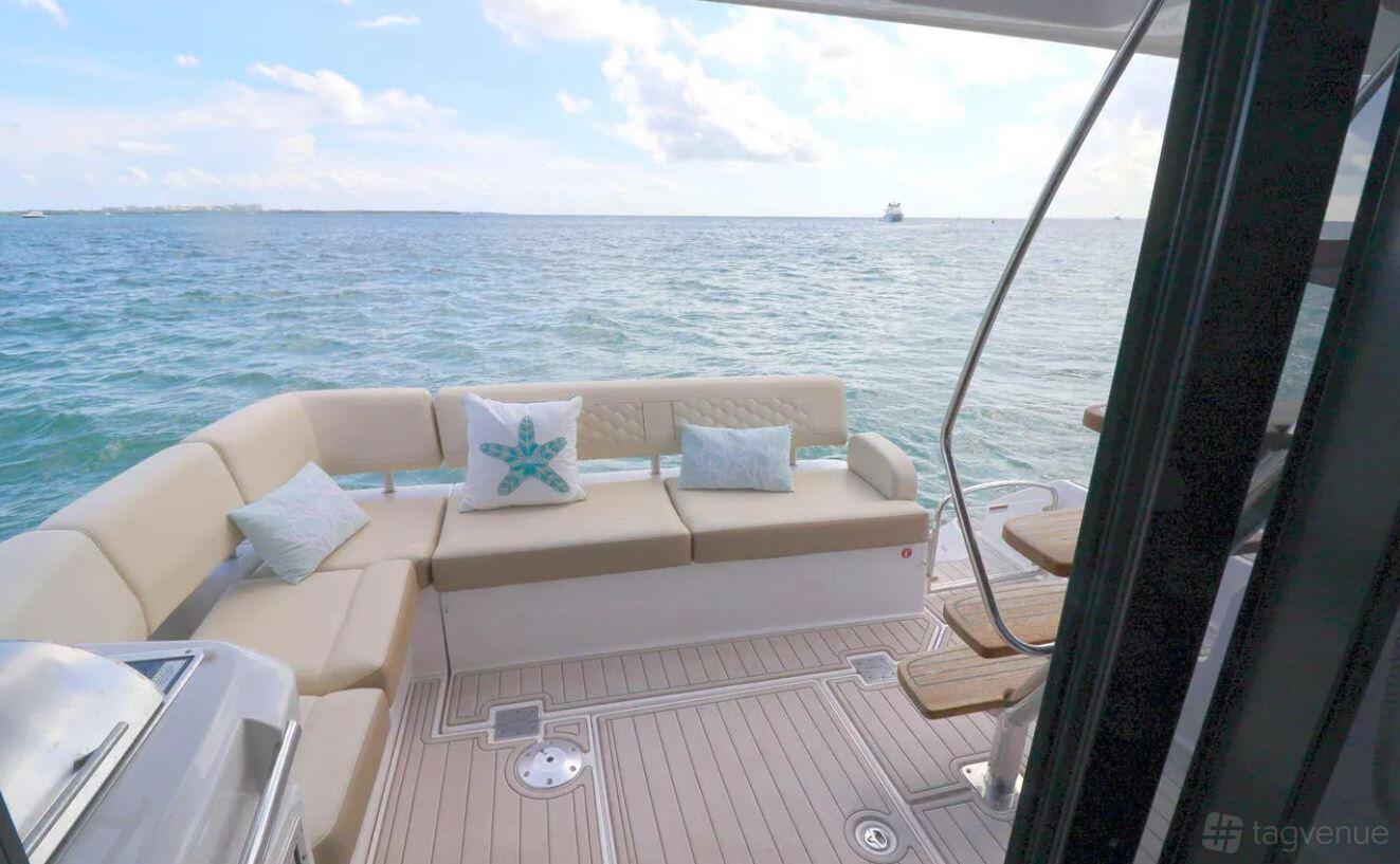 A yacht deck with cushioned seating, decorative pillows, and steps leading to the water at Beeyond Boats - Yacht Charters & Rentals.