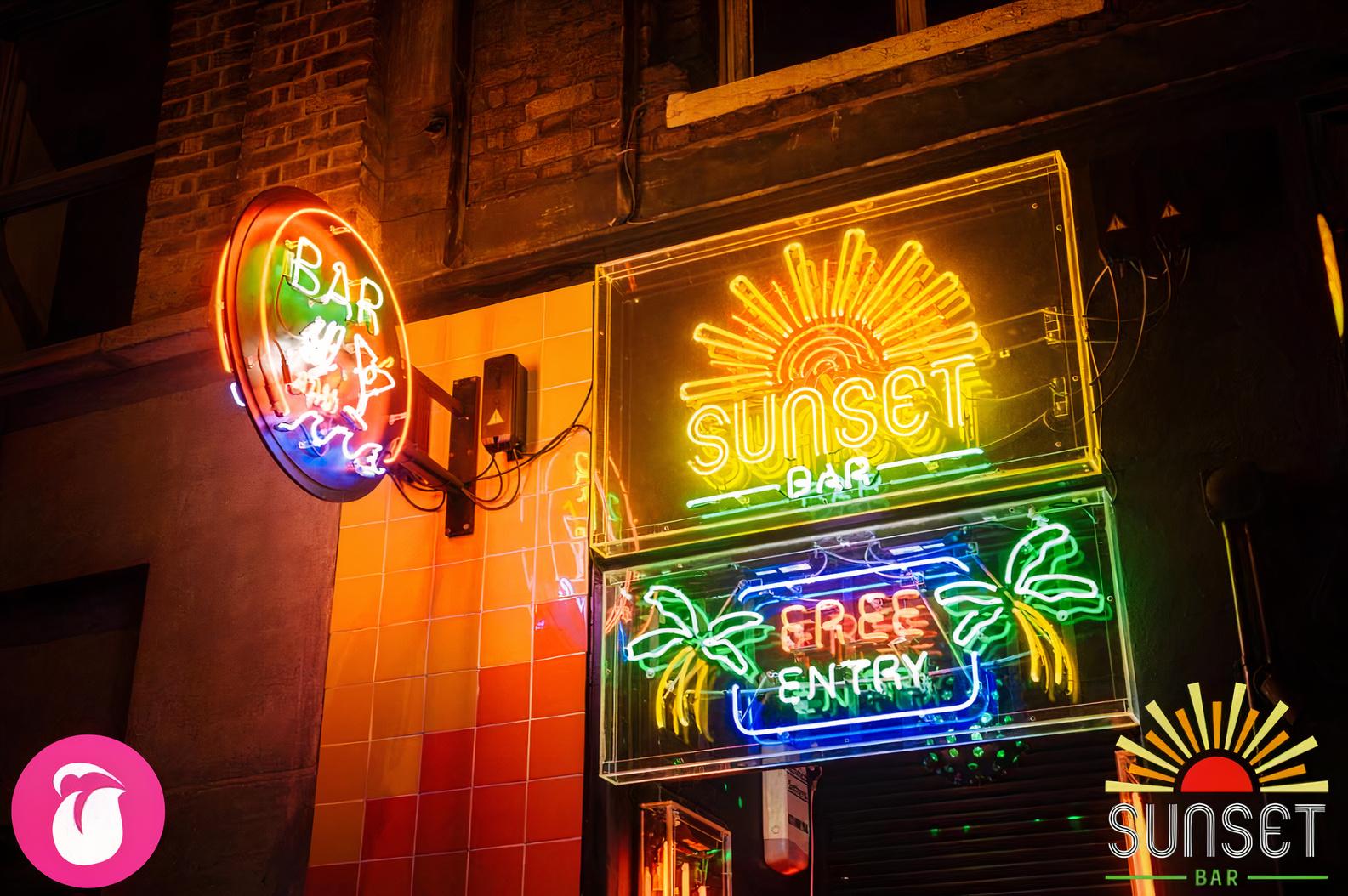 A pub with colorful neon signs, including palm tree and sun designs, on the exterior wall at Sunset Bar.