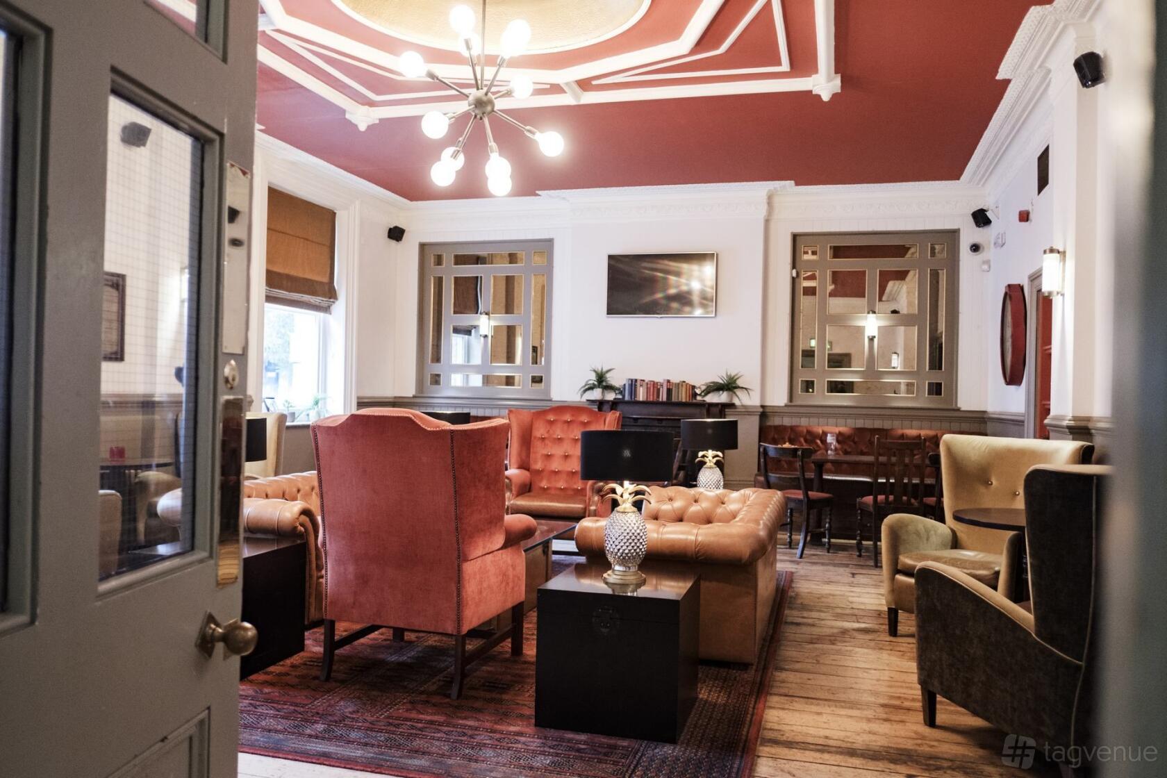 An event space with velvet armchairs, tufted sofas, a chandelier, and wood floors at The Drayton Court Hotel Drawing Room.