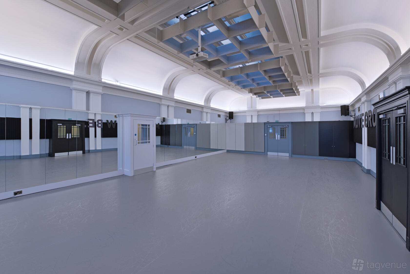 A dance studio with full-length mirrors, high ceilings, and large windows at Impact Dance Studio.