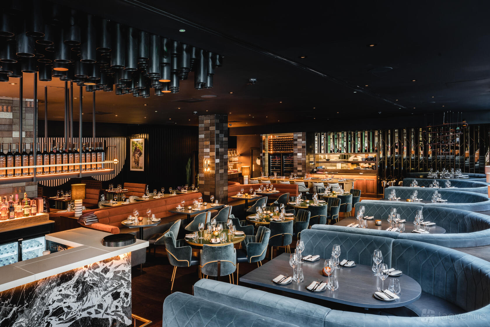 A restaurant with curved velvet booths, marble bar, and ambient pendant lighting at Gaucho Glasgow.
