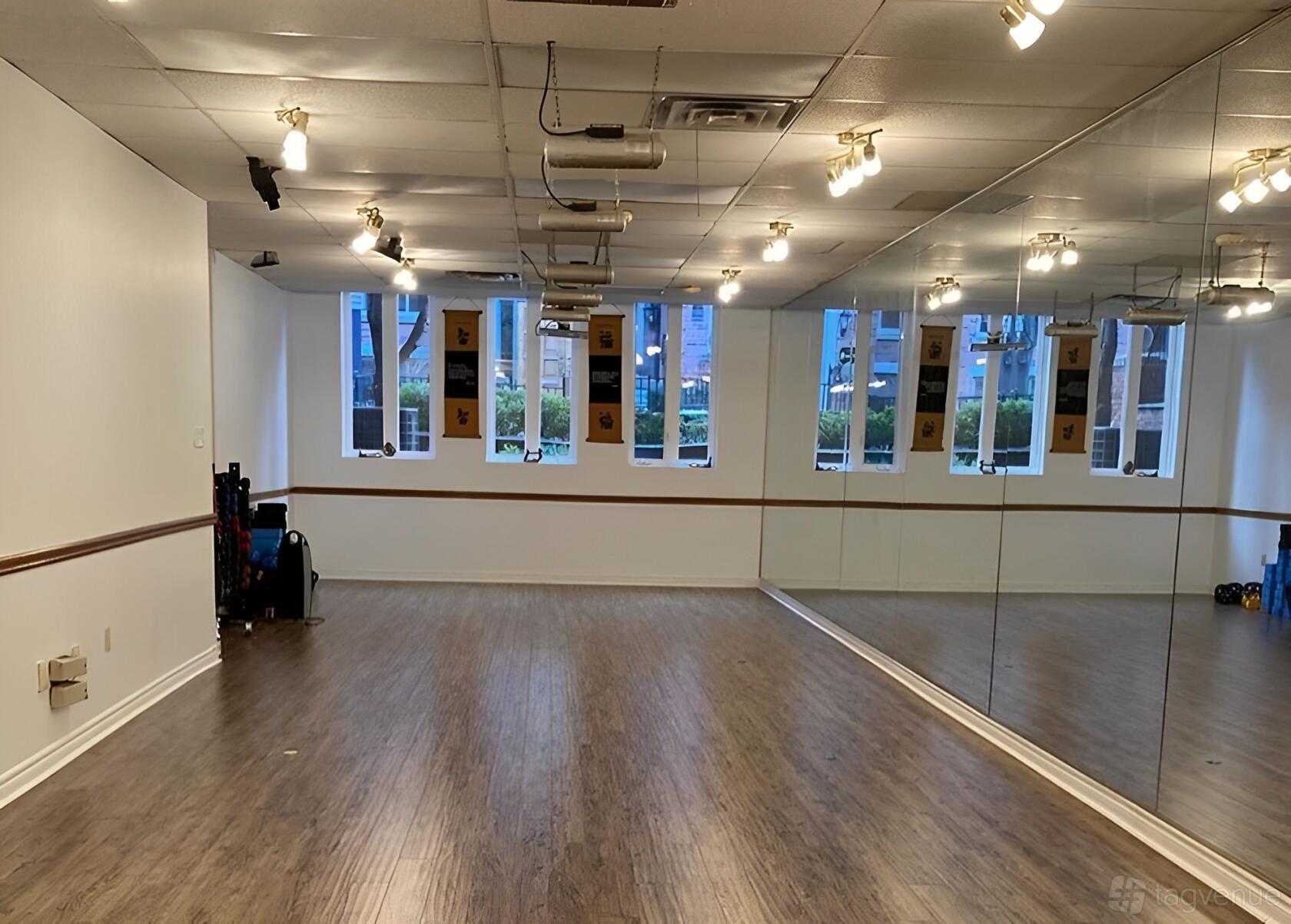 A yoga and pilates studio with mirrored walls, wood floors, and large windows at Holistic BodyWorx.