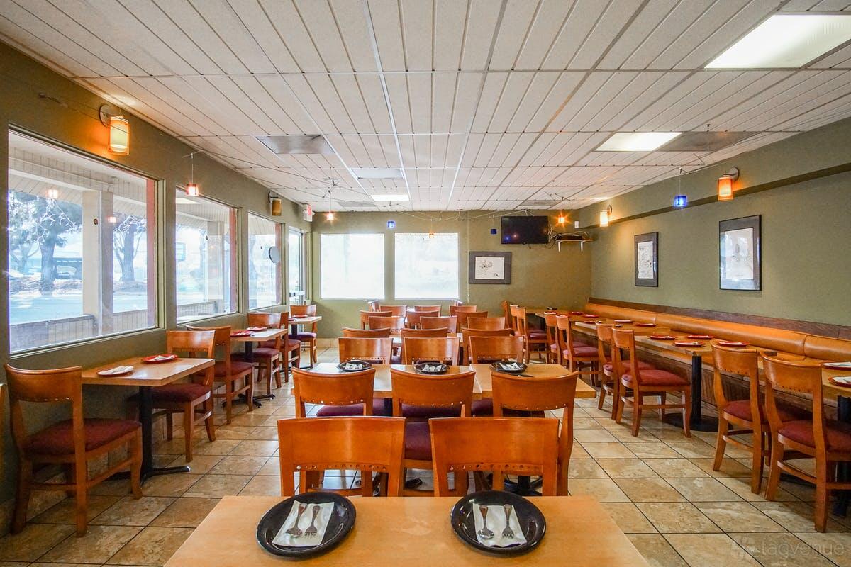 A cafe with natural light, framed art on olive walls, wood chairs, and tiled floors at Amber Cafe.