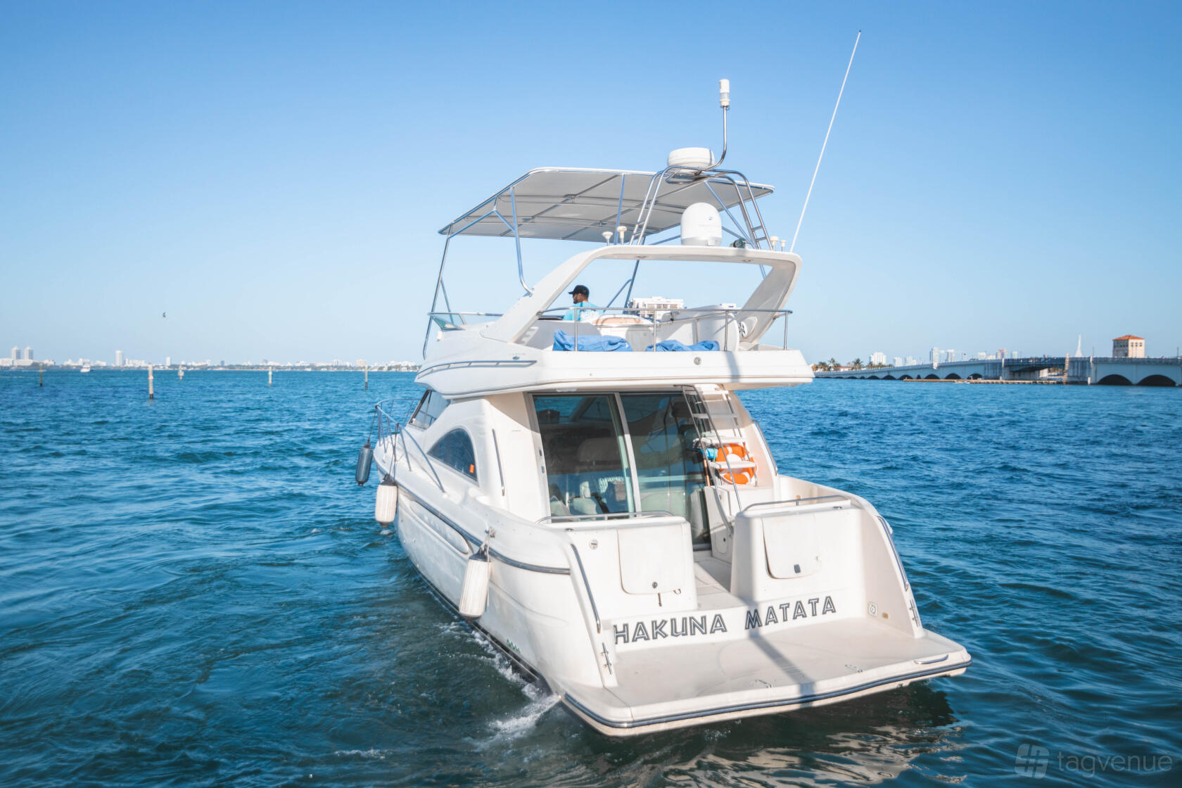 A yacht with an open rear deck and upper seating area on the water at Boat Rental Miami Beach 3480 NW.
