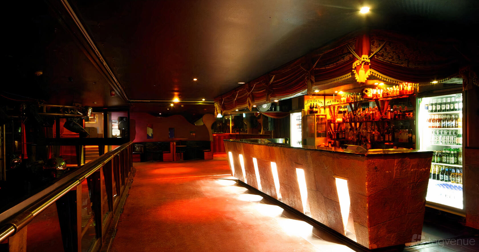 An event space in a nightclub with a long illuminated bar, draped curtains, and dim lighting at Chasers Nightclub and Venues.