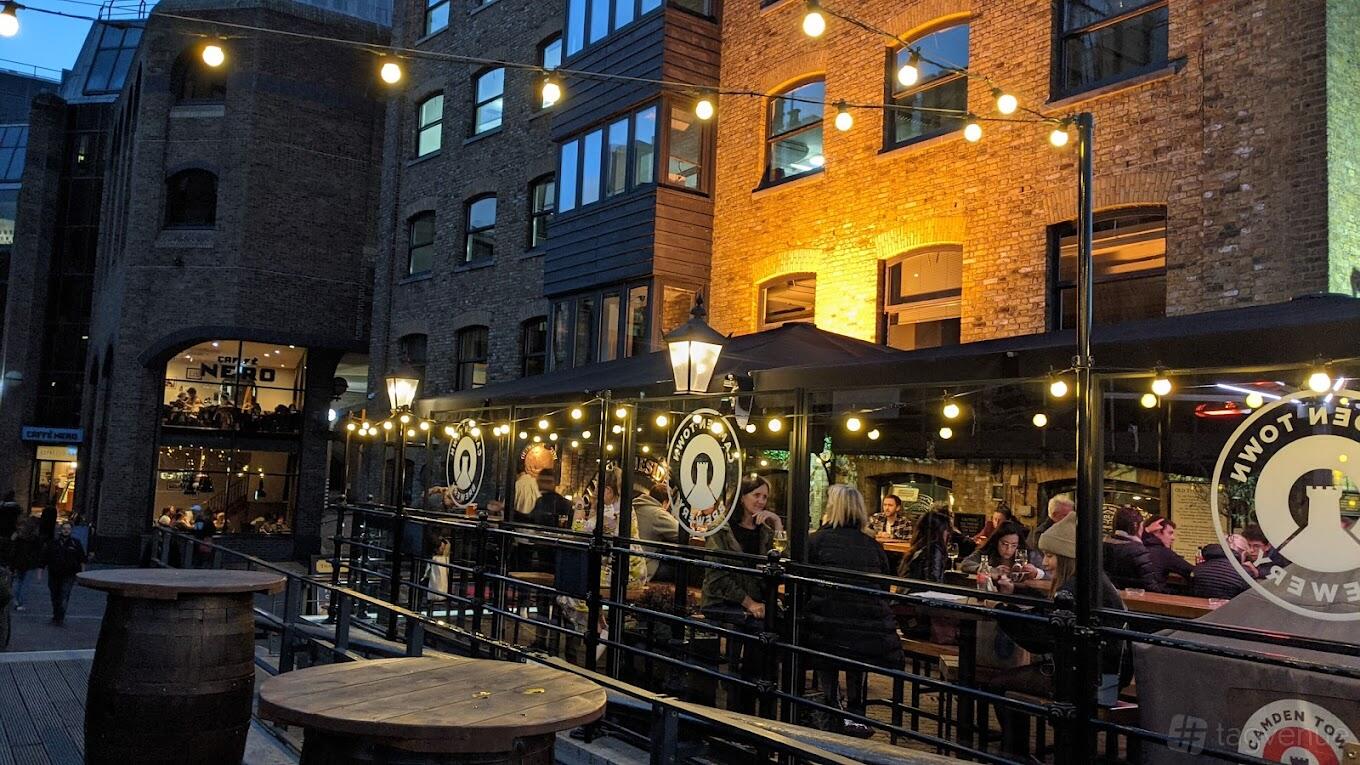 A terrace pub with string lights, outdoor seating, and exposed brick walls at The Old Thameside Inn.