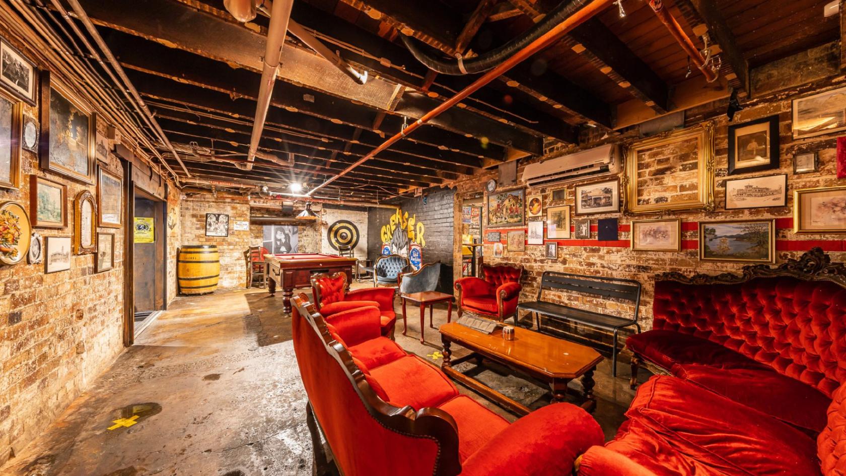 A function room in a pub with exposed brick walls, vintage red velvet sofas, and a pool table at The Prince Consort.