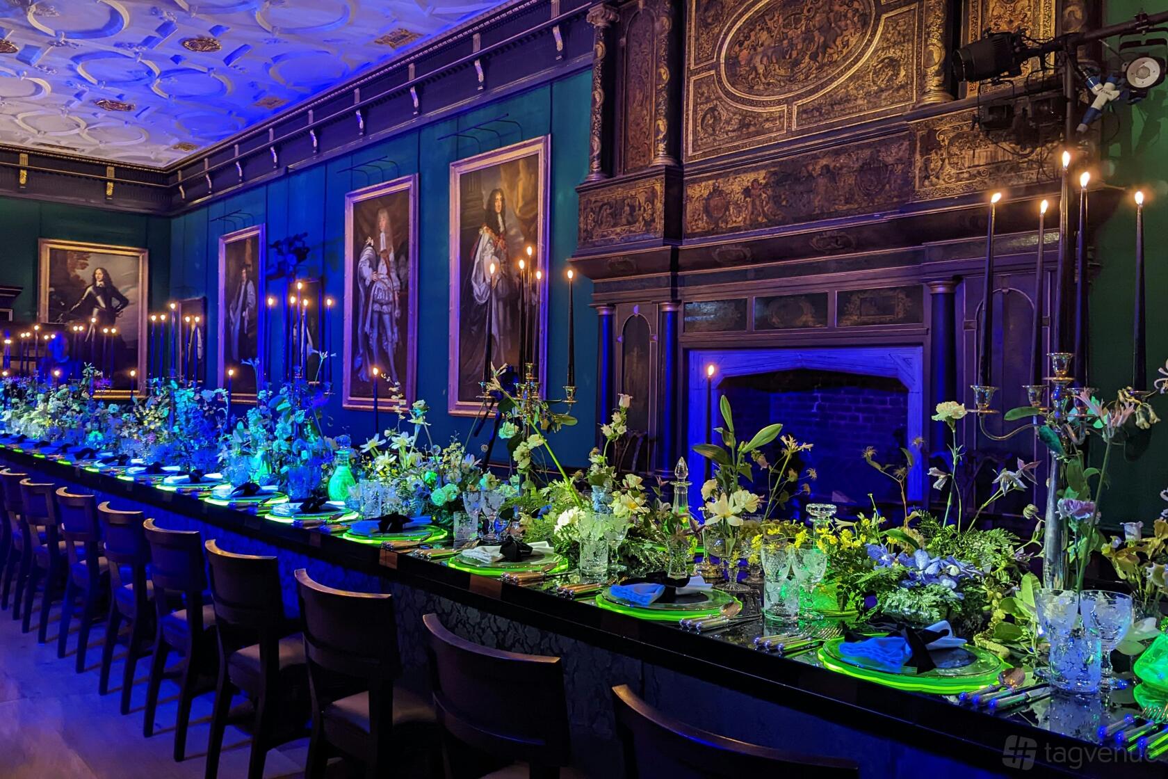 A historic hall with ornate wood paneling, candlelit banquet tables, and portrait paintings at The Charterhouse.