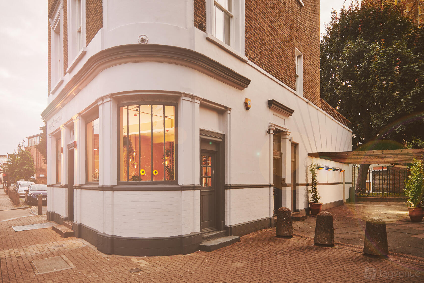 A pub with a white and brick exterior, large front windows, and a gray door at aspen & meursault.
