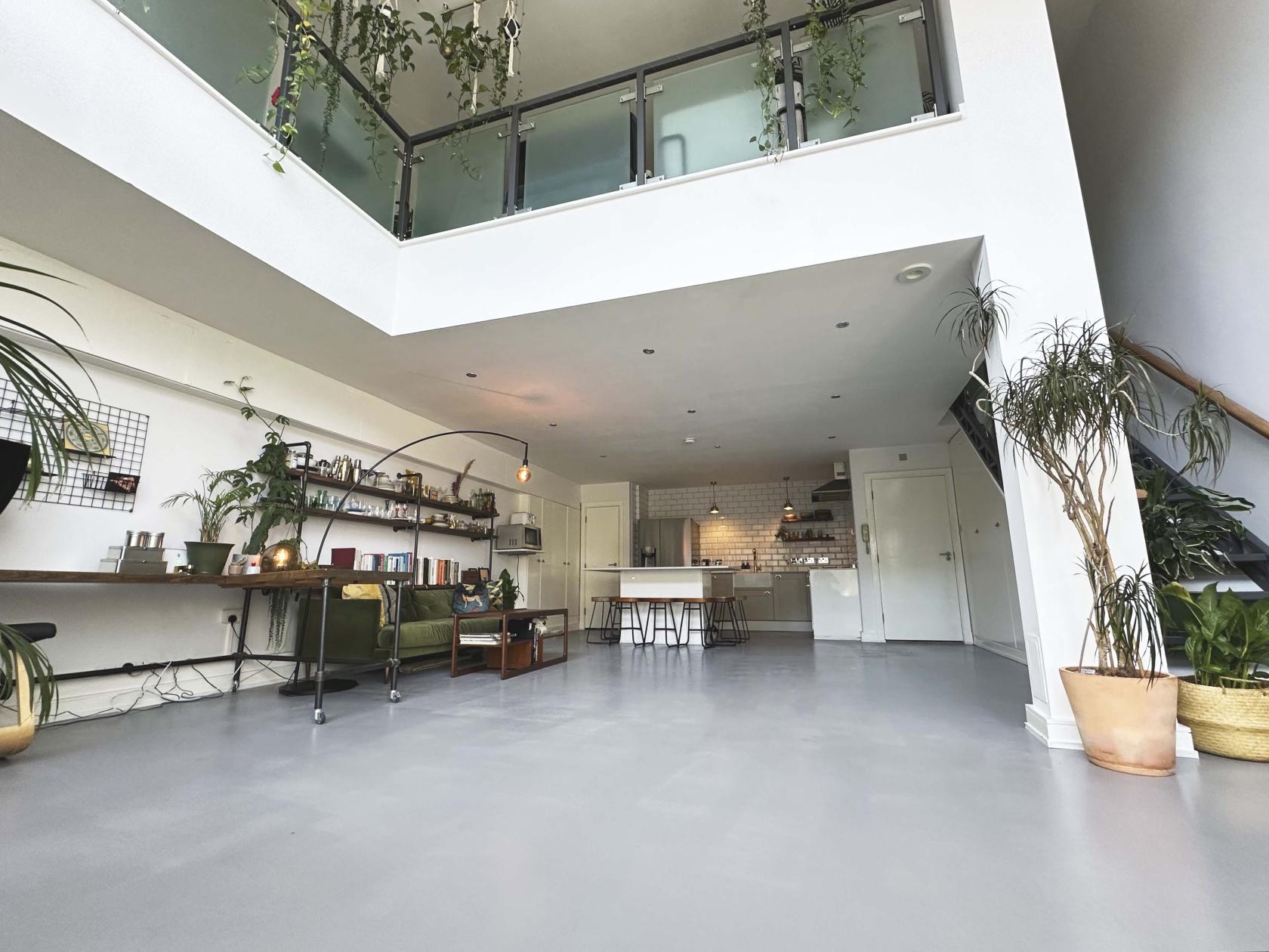 A photo studio with high ceilings, natural light, potted plants, and an open kitchen at MilkIt! Studios.