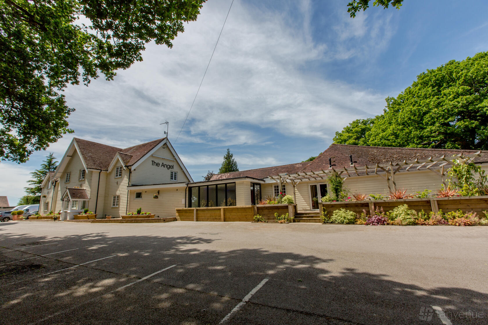 A hotel with cream clapboard exterior, gabled roof, and landscaped entrance at The Angel Hotel.