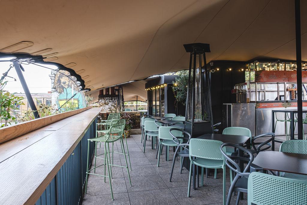 A covered terrace with string lights, outdoor heating, and green chairs at Lord Napier Star.