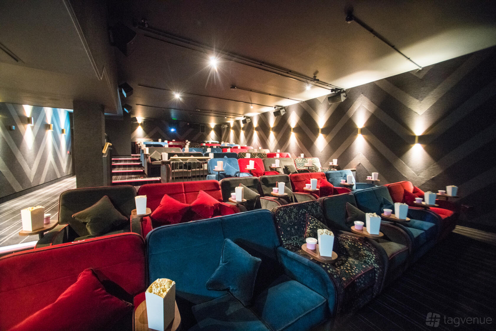 An auditorium with plush sofa seating, patterned walls, and individual cup holders at Everyman Glasgow.