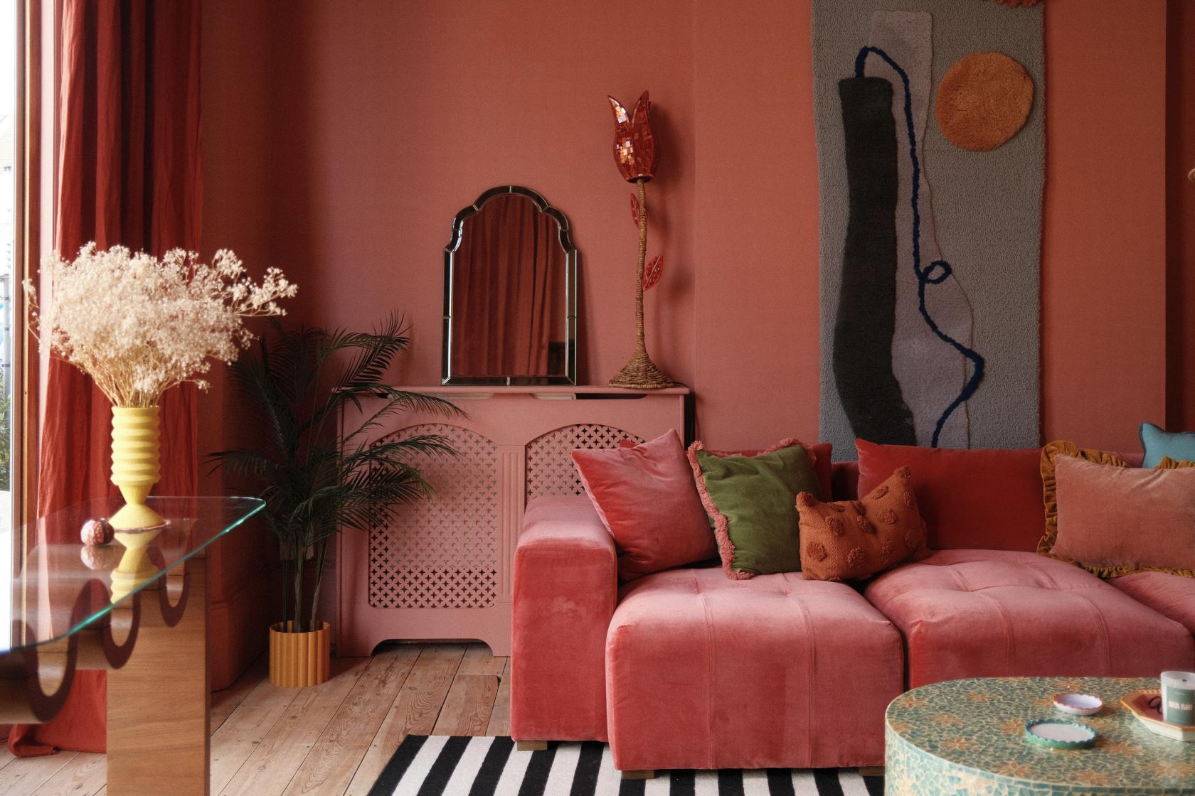 A photo studio with a plush pink sofa, textured wall art, and dried florals in the Marrakesh Room at Groovy House.