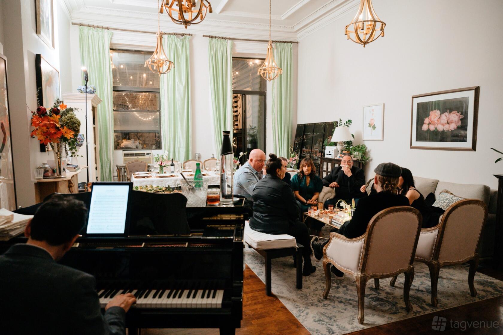 An event space in a restaurant with a grand piano, vintage armchairs, and large windows with green drapes at Supper Club NYC.