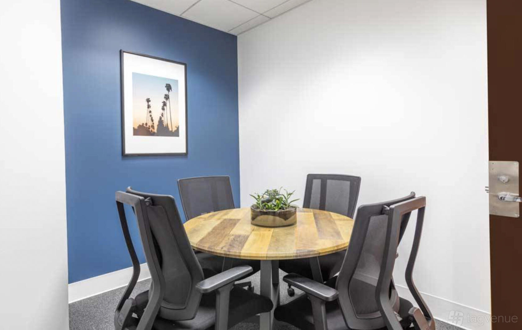 A coworking space with a small round wooden table, four mesh chairs, and a potted plant at Premier Workspaces - Executive Tower.
