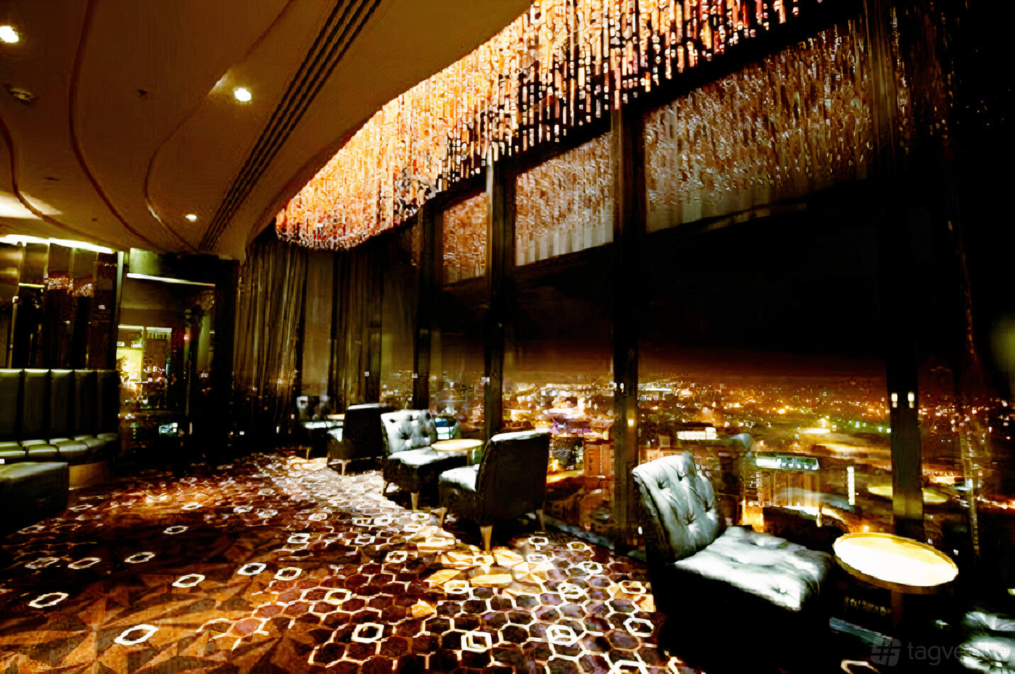 A lounge with floor-to-ceiling windows, plush armchairs, and a sparkling ceiling light feature at Cloud 23.