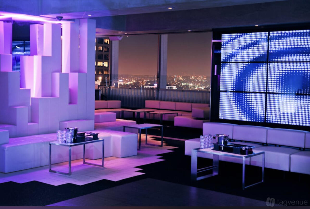 A lounge in a restaurant with white sofas, LED wall display, and floor-to-ceiling city views at Takami Sushi & Robata.