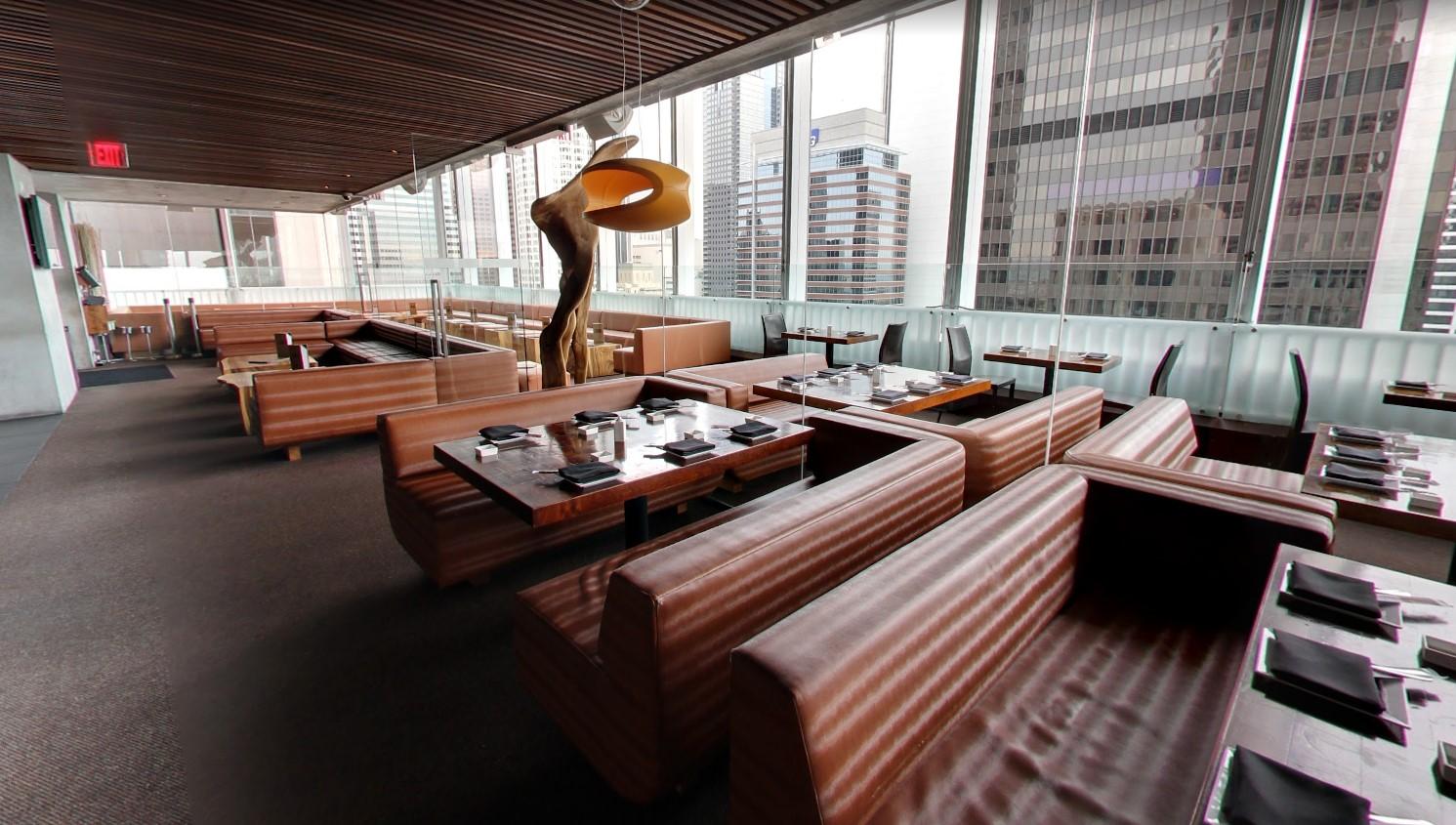 A restaurant with brown leather booths, floor-to-ceiling windows, and city skyline views at Takami Sushi & Robata.