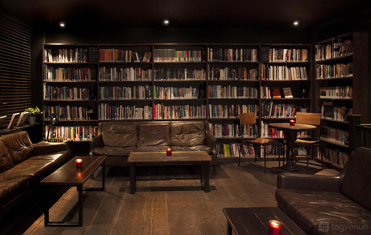 A cinema lounge with leather sofas, wooden tables, and walls lined with bookshelves at Close-Up Cinema.