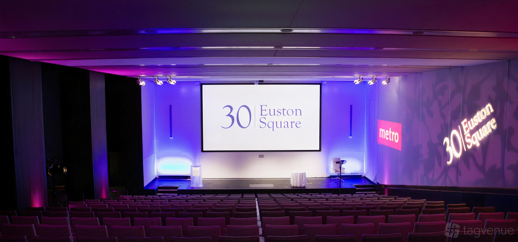 An auditorium with tiered seating, a large projection screen, and purple accent lighting at 30 Euston Square.
