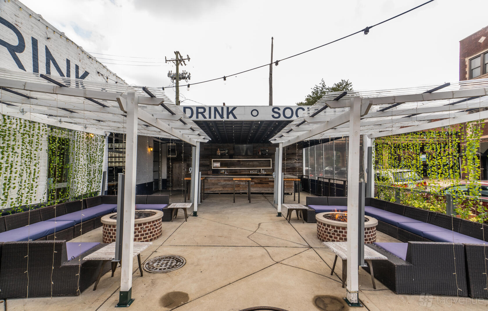 An outdoor restaurant patio with pergolas, string lights, circular fire pits, and cushioned couches at Bar Cocina Lakeview / Lincoln Park.