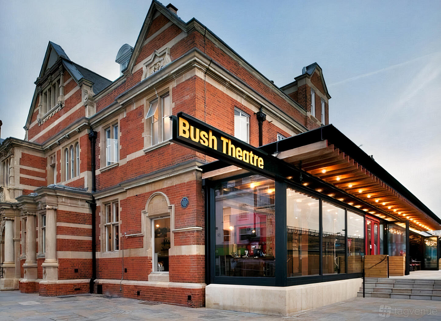 A theatre with a red brick exterior, modern glass entrance, and marquee sign at Bush Theatre.