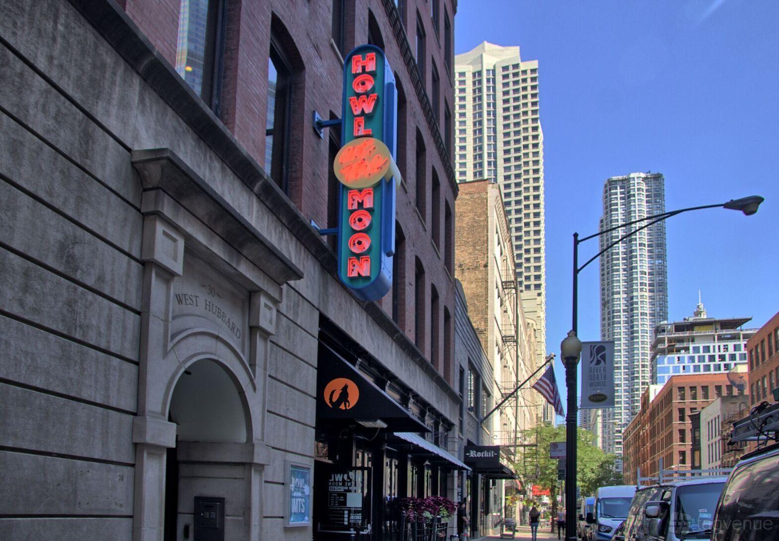 A pub with a neon vertical sign and brick facade at Howl at the Moon, Chicago.